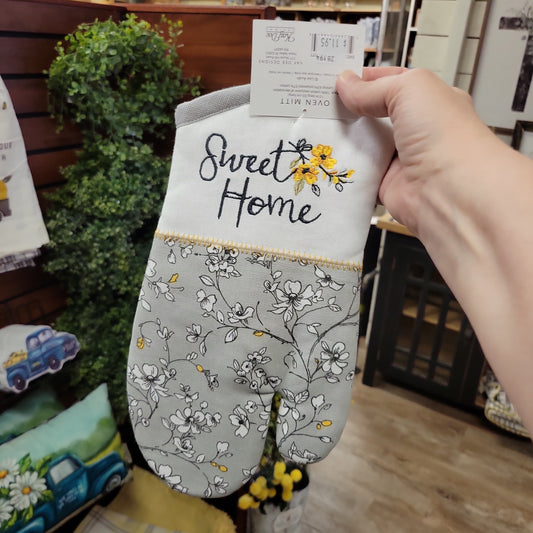 gray flowered oven mitt with white trim embroidered with gray stitching sweet home and yellow flowers