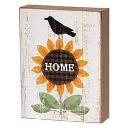 box sign with a sunflower that says HOME and a black crow on top