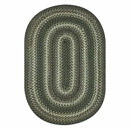 white background with an oval braided rug in shades of dark green, light green, and cream